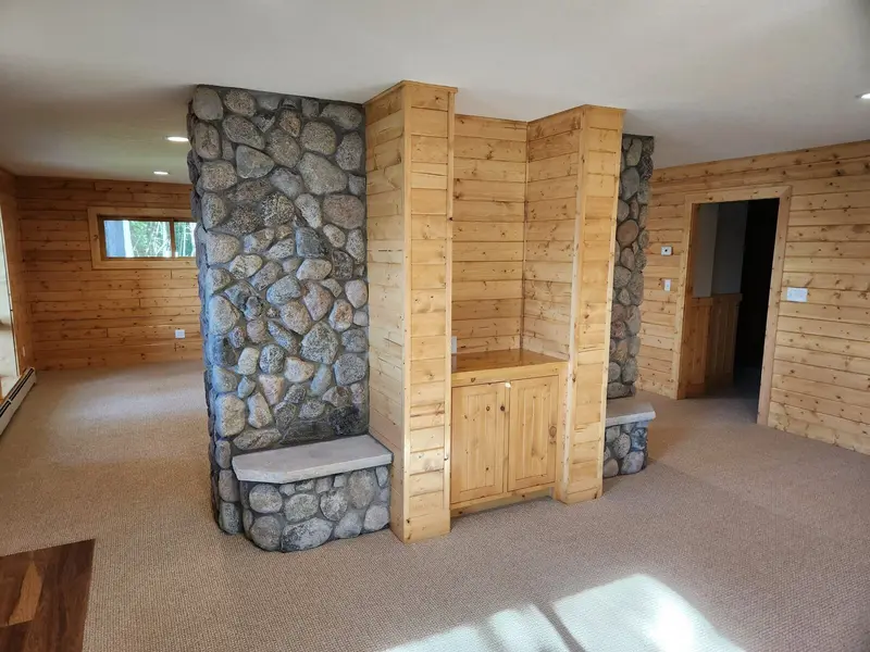 Finished basement family room with knotty pine walls and a fieldstone column
