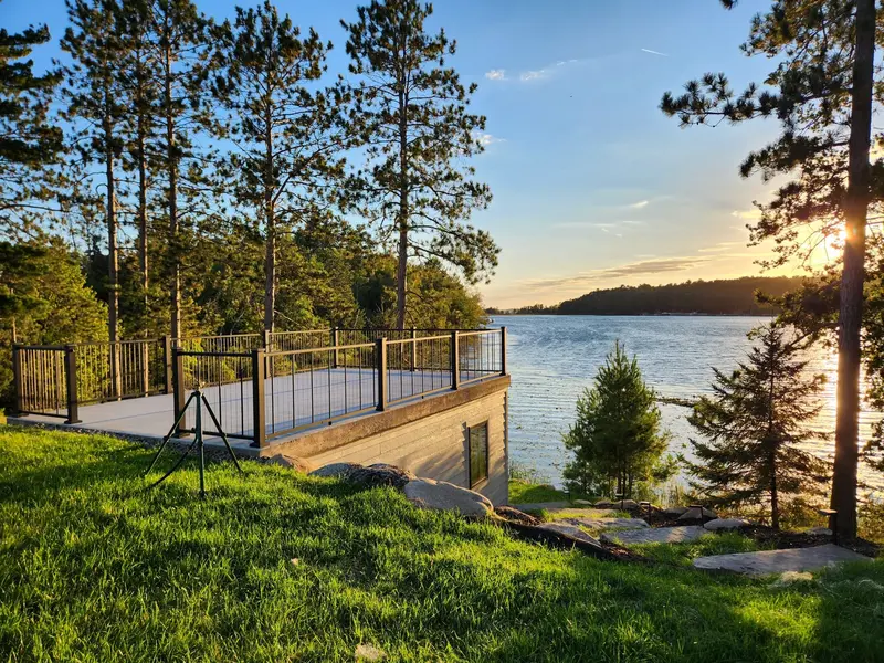 Lakeside rooftop deck with black aluminum railing at sunset